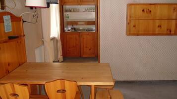 A kitchen with wooden cabinets, a built-in microwave, and a dining table with chairs.