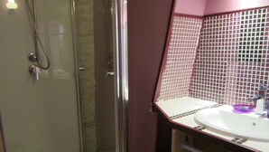 Une salle de bain avec une douche à parois de verre, un lavabo blanc et un mur carrelé.
