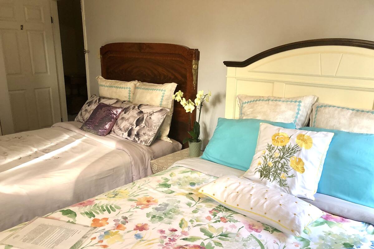 Un dormitorio con dos camas, cada una con ropa de cama de estampado floral y varias almohadas.