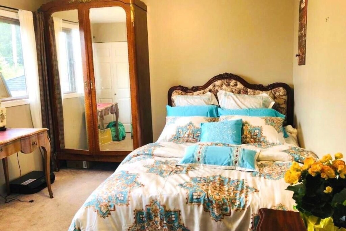 Un dormitorio con una cama, un armario de madera, un espejo y un escritorio.