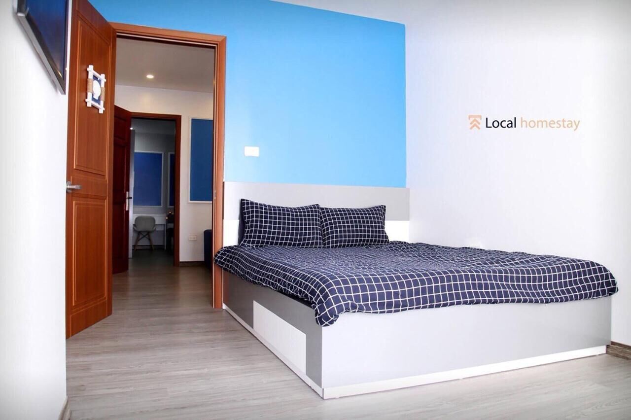 A bedroom with a bed, a door, and a wall with a logo.