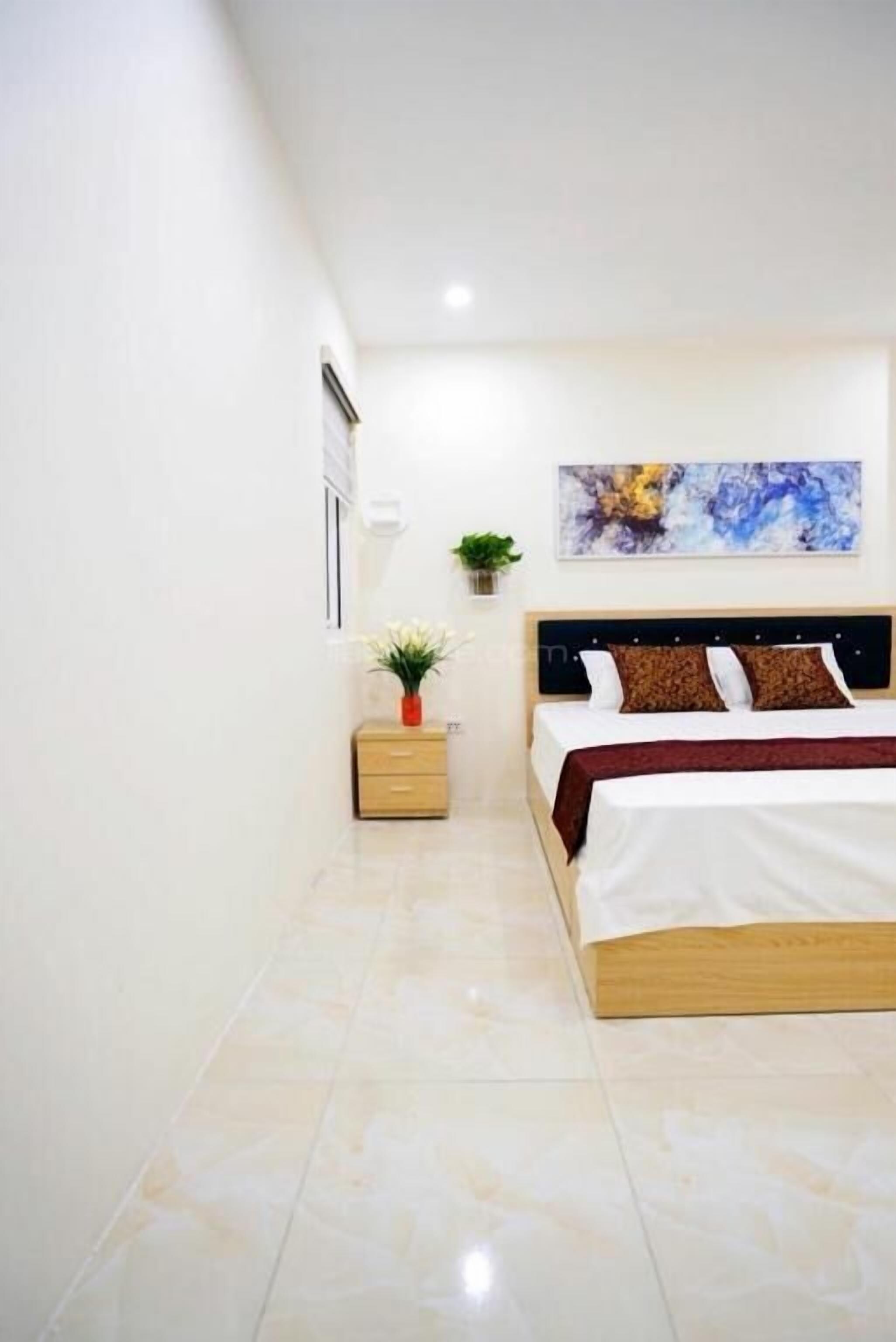 Un dormitorio con cama, mesita de noche y una obra de arte en la pared.
