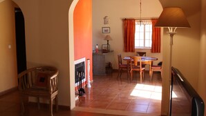 A dining area with a table and chairs, a fireplace, and a lamp.