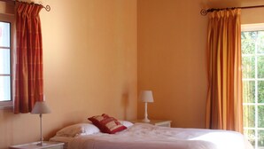 A bedroom with a bed, a nightstand, a lamp, and a window with curtains.