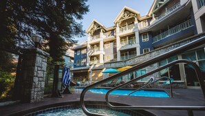 A hotel with a pool area, including a hot tub and lounge chairs. - Pet-Friendly | Whistler | Shuttle, Pool + Hot Tub (Whistler)