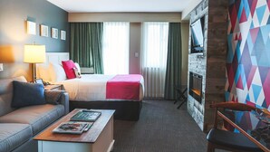 A hotel room with a bed, a sofa, a coffee table, a fireplace, and a colorful wall. - Pet-Friendly | Whistler | Shuttle, Pool + Hot Tub (Whistler)