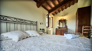 Une chambre à coucher avec un grand lit, une commode en bois, un miroir et un radiateur.