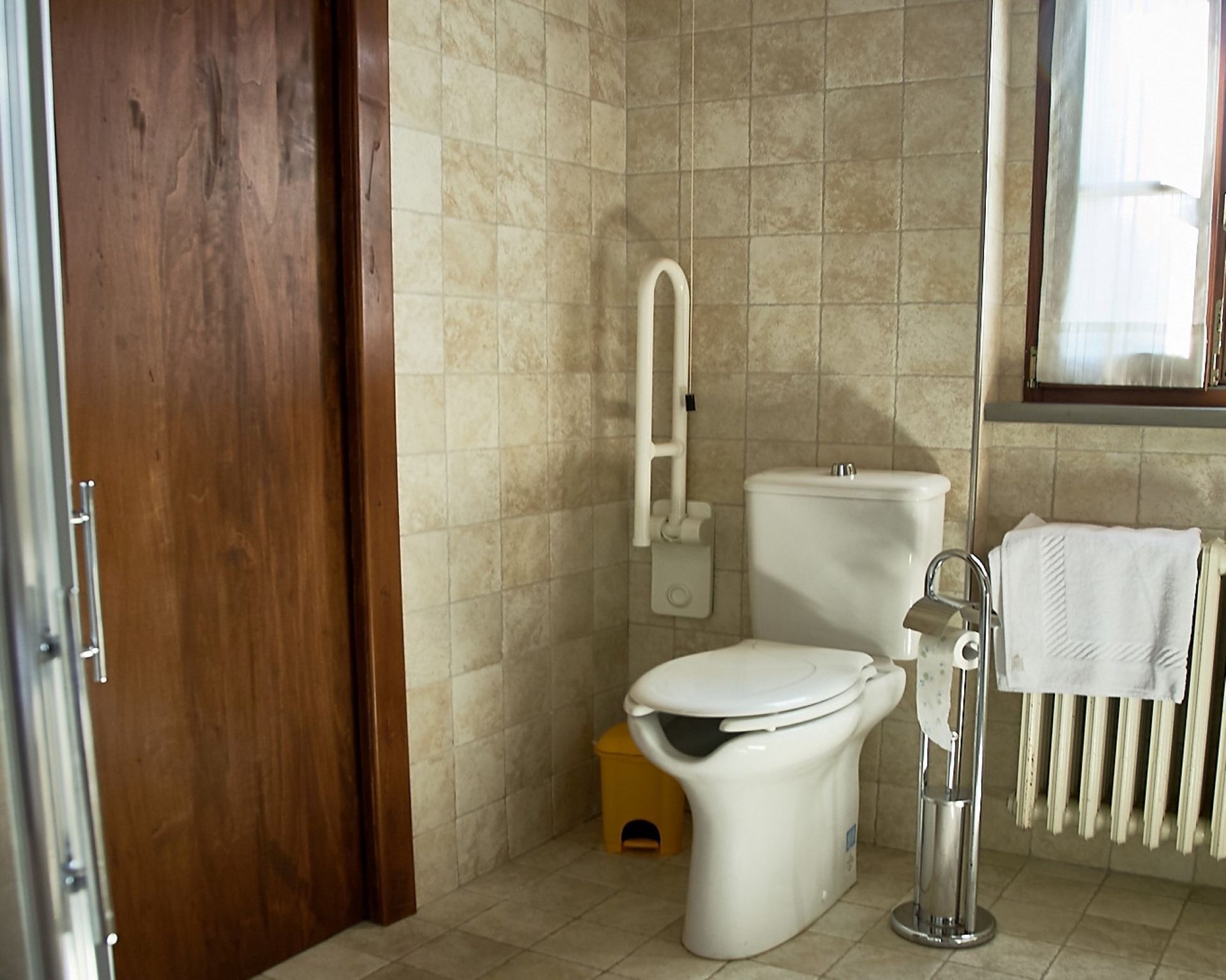 Een badkamer met toilet, bidet en een handdoekhouder.