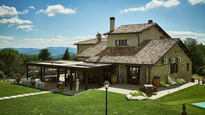 Une maison en pierre avec un toit en tuiles, un patio couvert et une pelouse bien entretenue.