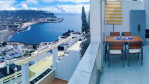 Un balcone con vista sul mare e una zona pranzo con tavolo e sedie.