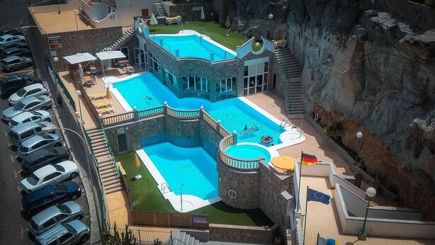 Un hotel con diverse piscine, un ristorante e un'area parcheggio.