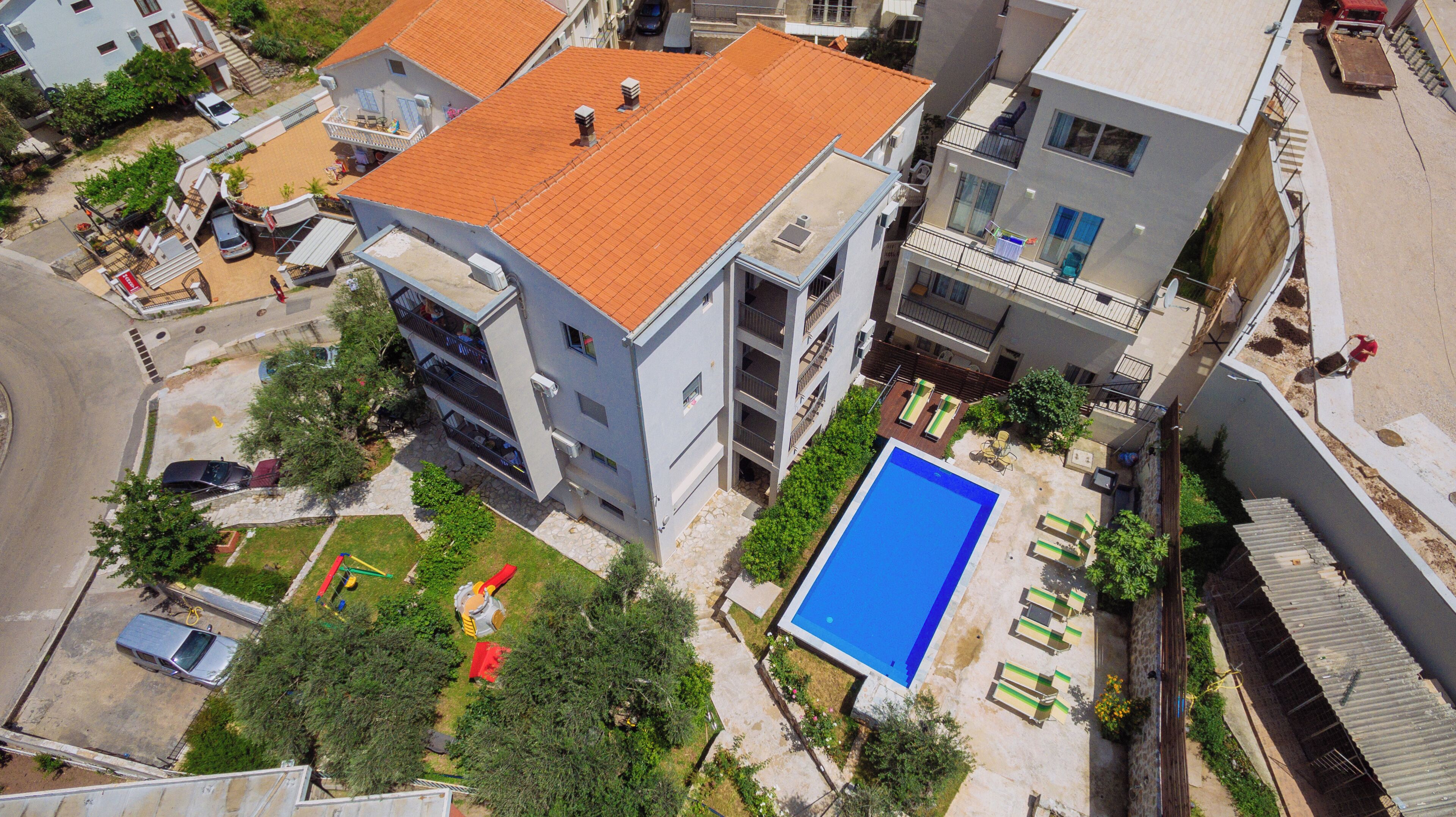 Vista aérea de un edificio residencial con terraza en la azotea, piscina y un pequeño jardín.