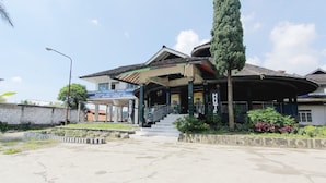 A building with a covered entrance, a staircase leading to the main entrance, and a signboard.
