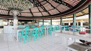 A spacious indoor area with a high ceiling, a central column, and multiple tables and chairs.
