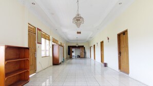 A long, narrow hallway with tiled flooring, wooden doors, and a chandelier.