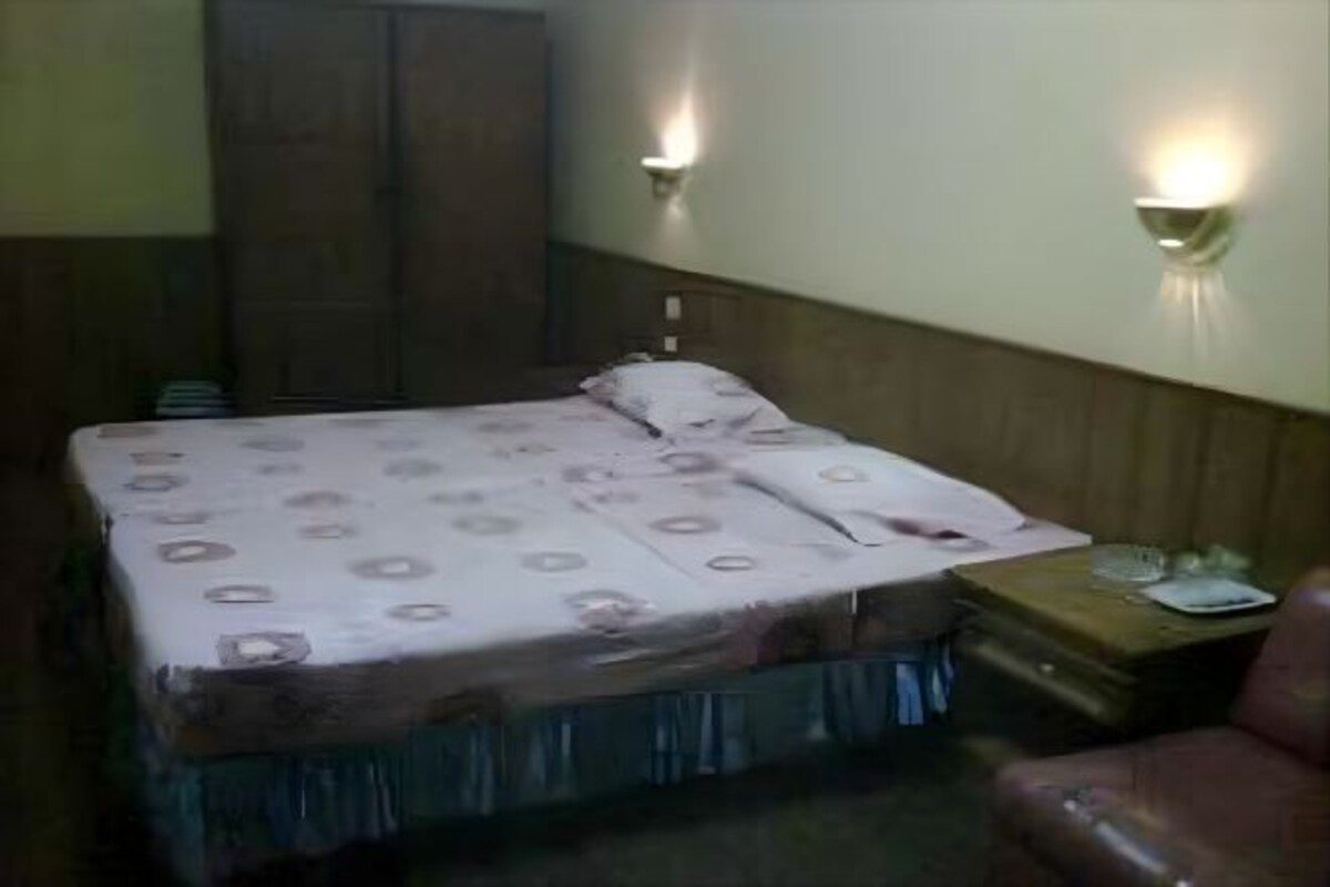 A bedroom with a bed, nightstand, and wall-mounted lights.