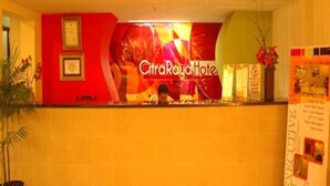 Un comptoir d’accueil surmonté d’une grande enseigne indiquant « Hôtel CitraRayah ».