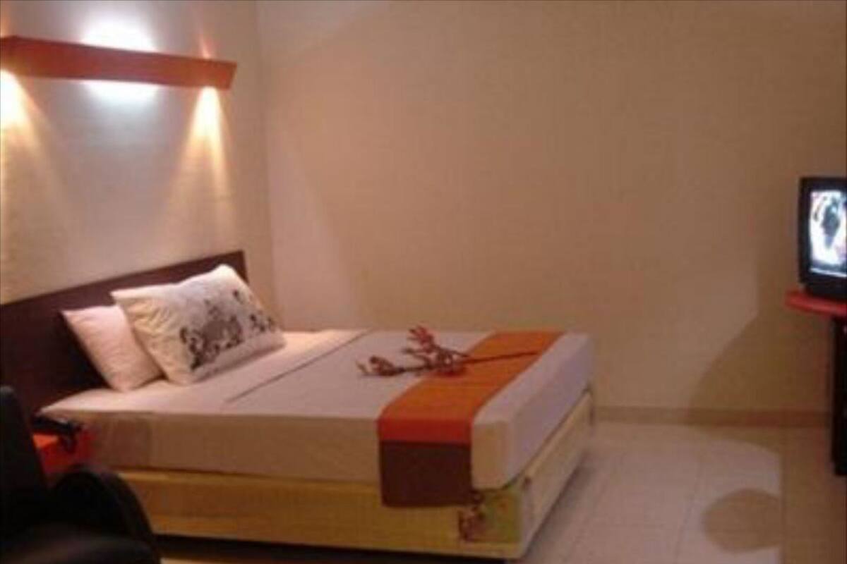 A hotel room with a bed, a television, a chair, and a small table.
