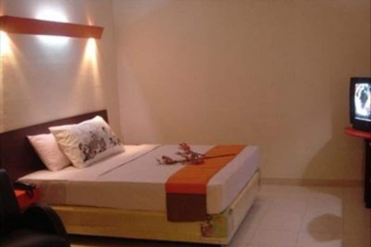 A hotel room with a bed, a television, a chair, and a small table.