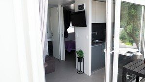 A modern, compact living space with a kitchenette, a small dining area, and a sliding glass door leading to an outdoor area. - Camp Milo moje (Gradac)