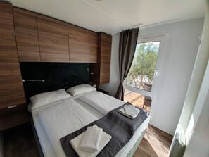 A bedroom with a bed, wooden headboard, and a window with curtains.