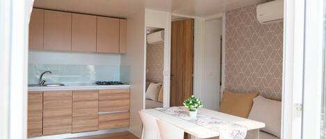 A compact kitchen with wooden cabinets, a white countertop, and a dining area with a table and chairs.