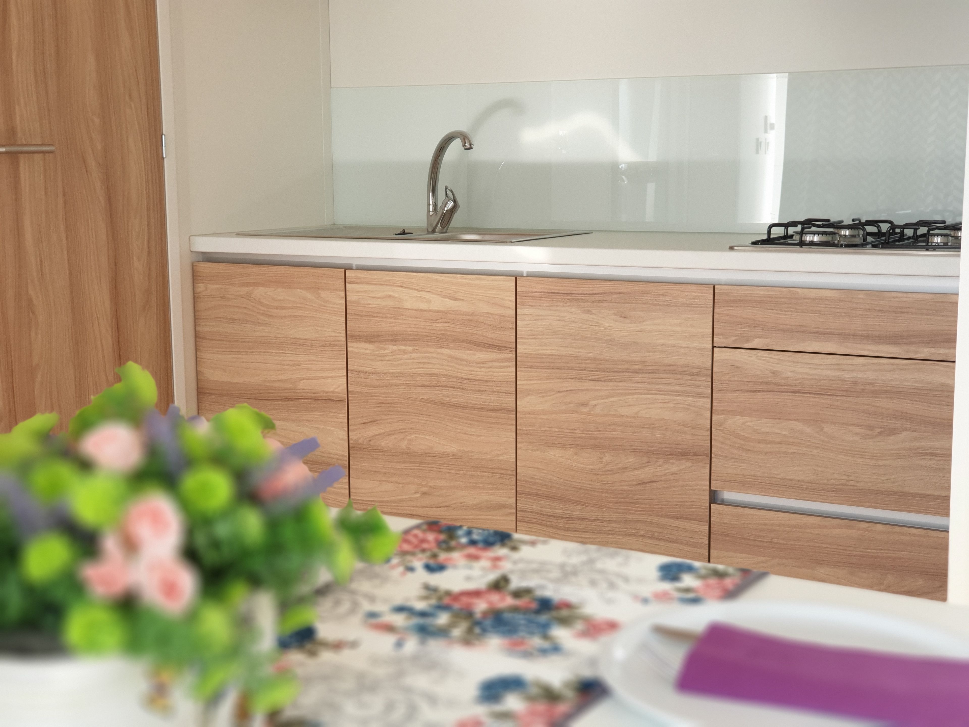 A modern kitchen with wooden cabinets, a stainless steel sink, and a gas stove.