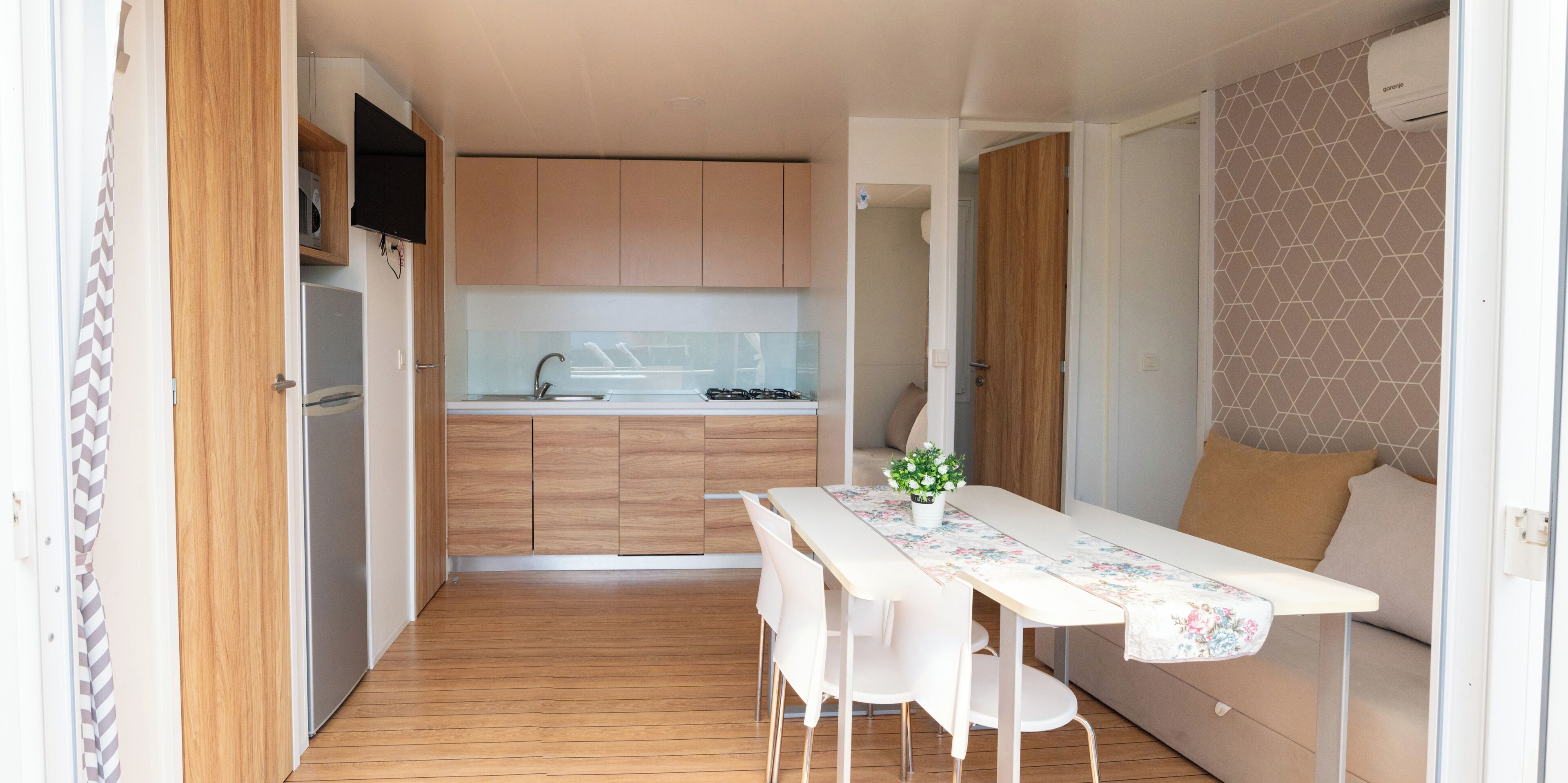 A compact kitchen with wooden cabinets, a white countertop, and a dining area with a table and chairs.
