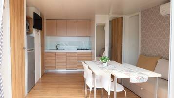 A compact kitchen with wooden cabinets, a white countertop, and a dining area with a table and chairs.