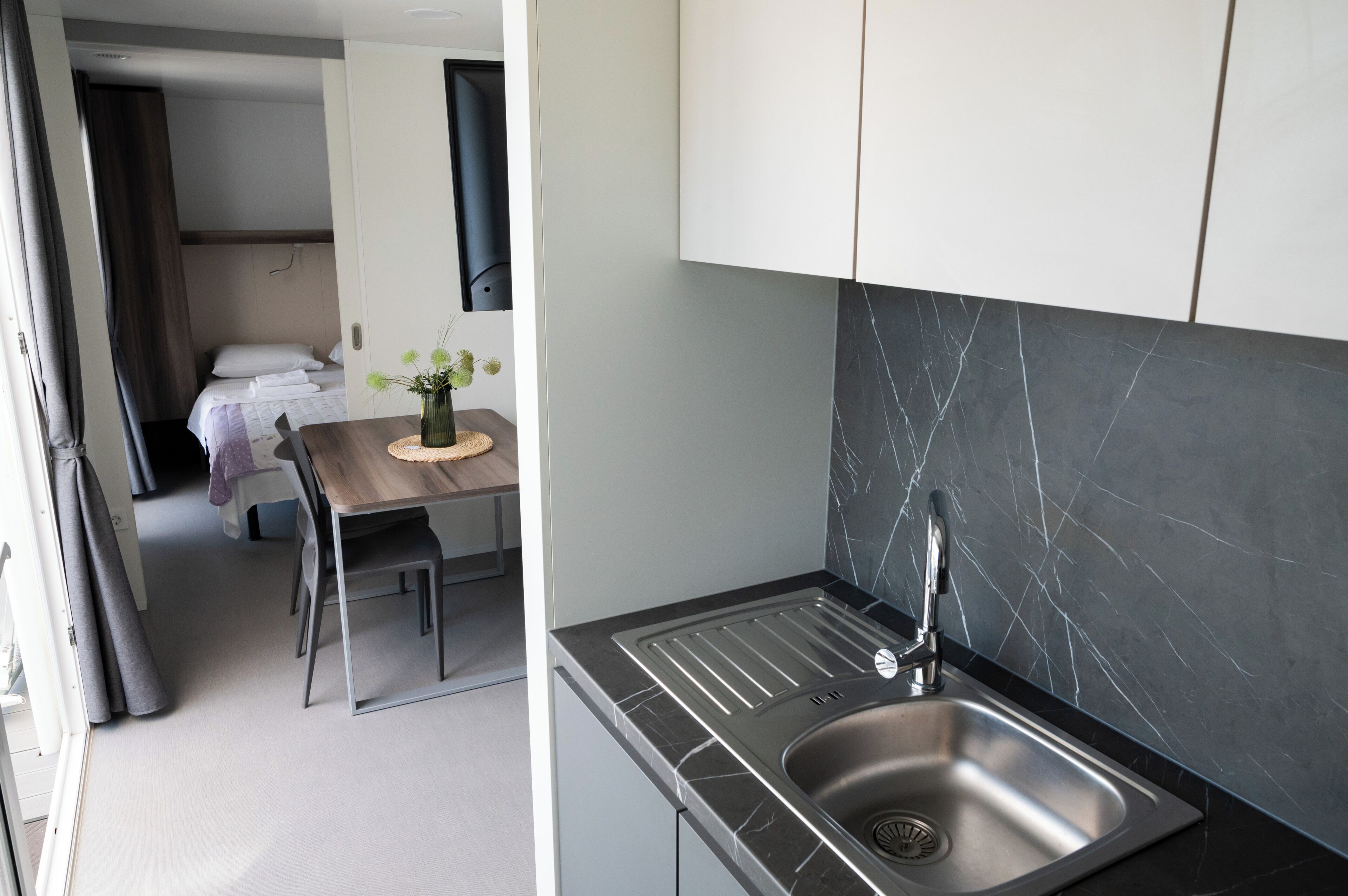 A compact kitchen with a modern sink and a dining area with a table and chairs.