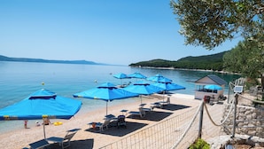 A beach with blue umbrellas, sun loungers, and a small building. - Camp Milo moje (Gradac)