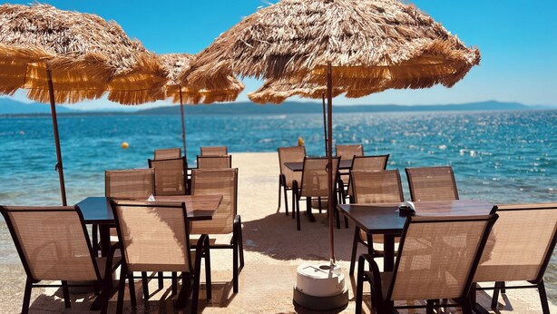 A beachside restaurant with tables and chairs under thatched umbrellas, overlooking the sea. - Camp Milo moje (Gradac)
