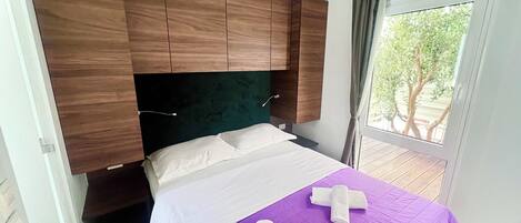 Un dormitorio con cama, cabecero de madera y ventana con vista a árboles.