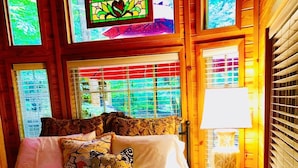 Een gezellige slaapkamer met een bed, kussens, een nachtkastje en een lamp.