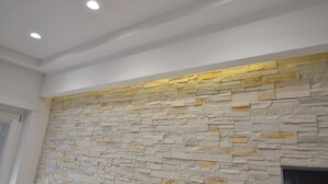 Ein Zimmer mit Steinwand und eingelassenen Deckenleuchten.