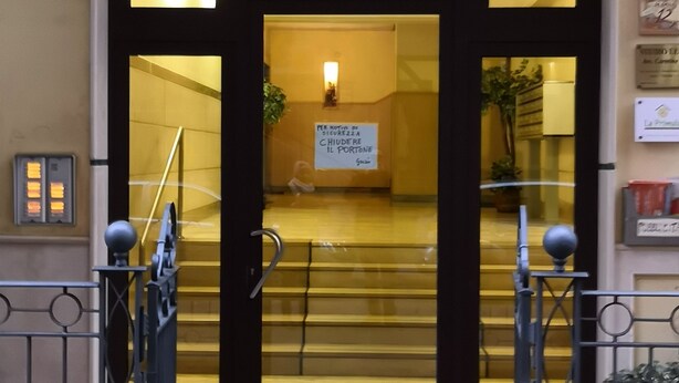 Ein Hotel Eingang mit Glastür, einem Schild in Italienisch und einem gefliesten Vorbereich.
