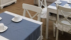 Ein Essbereich mit einem Tisch für zwei Personen, einem weißen Sessel und einem weißen Schrank mit Tür.