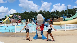 A mascot character in a water park with a pool and slides in the background. - The Silver Spur Resort - Campsite (Canton)