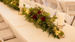 A long table with white tablecloths, candles, and floral centerpieces in a rustic wooden room. - The Silver Spur Resort - Campsite (Canton)