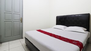 A single bed with a white mattress and a red blanket, a grey door, and a white wall. - Wisma Lamida 2 Syariah (Jakarta)