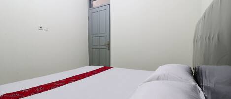 A bedroom with a bed, a door, and a light switch on the wall.