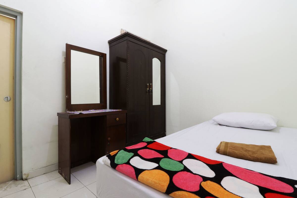 A bedroom with a bed, a dresser, a mirror, and a door.