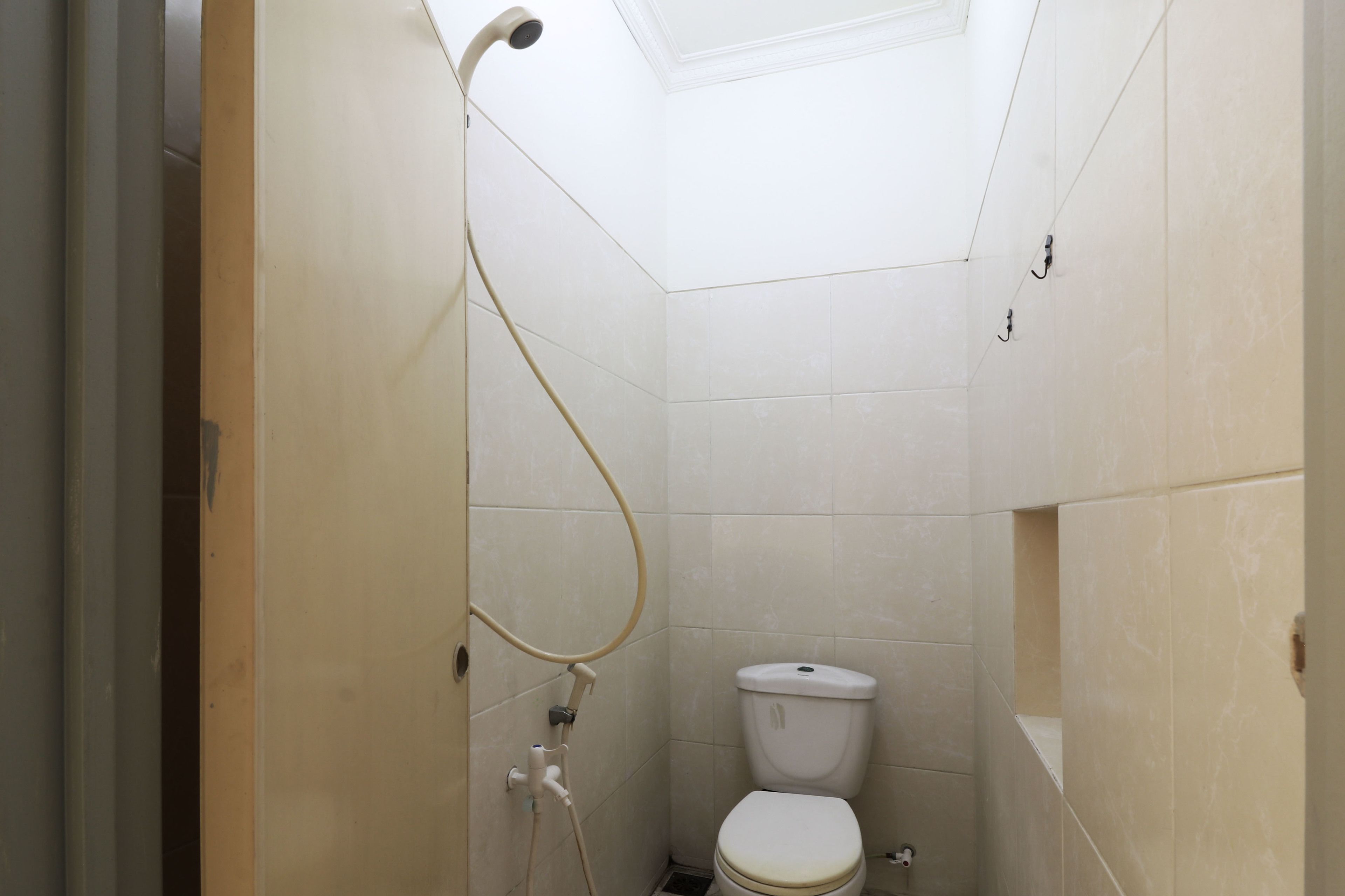 A small, compact bathroom with a toilet, a shower, and a skylight.