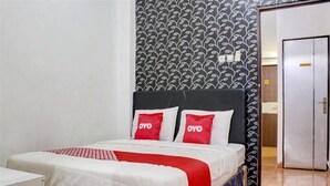 A hotel room with a bed, a bedside table, and a patterned wall. - Semata Wayang Syariah Homestay (Banjarbaru)