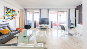 A modern living room with a glass coffee table, leather sofa, and a dining area with a glass table and metal chairs. - Apartment Eze Seaside in 1st line facing the sea (Èze)