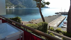 A balcony with a clear view of a calm sea, a rocky shoreline, and a distant mountain range. - Apartment Eze Seaside in 1st line facing the sea (Èze)