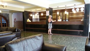 A lobby with leather sofas, a reception desk, and a clock.