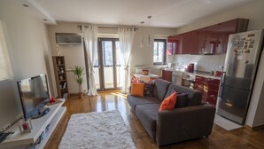 A modern living room with a grey sofa, a white rug, and a flat-screen TV. - Desire City Center Apartment Terazije (Belgrade)