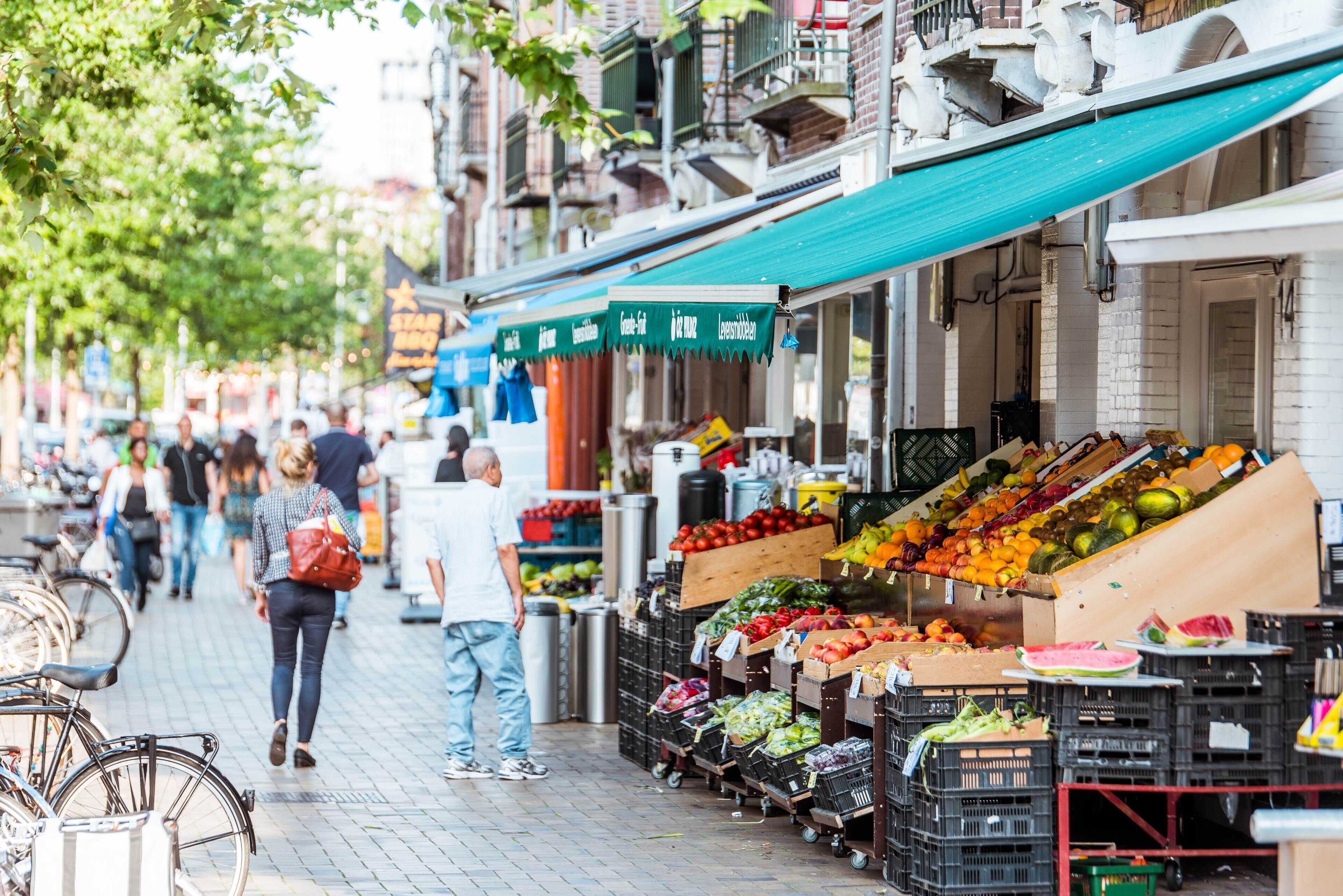 A street market with various stalls selling fresh produce.