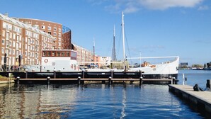 En lystbådehavn med fortøjede både, en bygning med mange vinduer og en klar himmel.